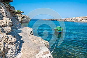 A green fishing boat bobs in a sheltered inlet near Polignano a Mare, Puglia, Italy photo