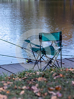 Green chair on the water against a background of autumn trees and blue sky