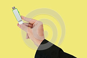 Green flash drive on hand with isolated yellow background