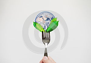 Green food, environmental concept. Hand holding fork with leaves and globe. Element of this image are furnished by NASA