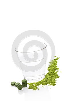 Green food supplements and a glass of water.