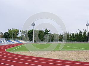 Green football field and red running track in the stadium. Running track on a stadium background. Sports concept. Copy