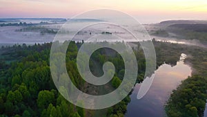 Green forest covered  in fog. River flowing  along rural area