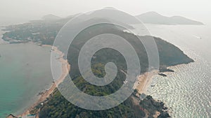 Green forest on hilly island with sand beaches upper view