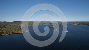 Forest and lakeshore with islands at Lake Siljan from above with blue sky in Dalarna, Sweden photo