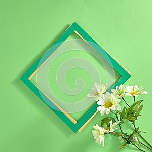 Green frame and bouquet of white daisy flowers on a green background. Text space. Top view. Minimal style