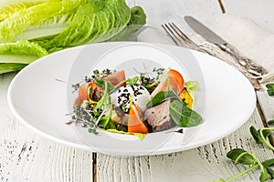 A green French bistro style salad with poached egg and chives on a white plate and table setting photo