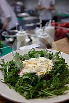 A green French bistro style salad with poached egg and chives on a white plate and table setting. photo