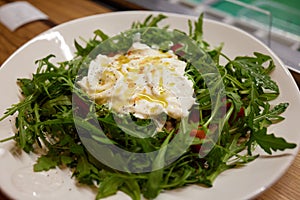 A green French bistro style salad with poached egg and chives on a white plate and table setting. photo