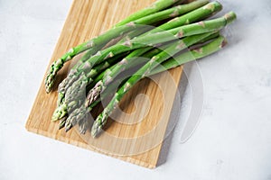 Green fresh asparagus on a wooden board on a white background. Copy space