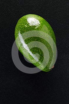 Green fresh avocado over black background close-up