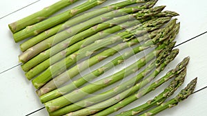 Green fresh and healrhy asparagus placed on a white wooden table. Top view. Close up.