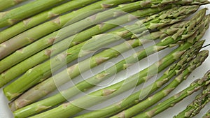 Green fresh and healrhy asparagus placed on a white wooden table. Top view. Close up.