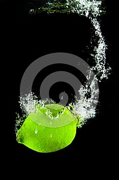 Green fresh lime fruit under water with reflection. Healthy cytrus lemon vegetable splashing into clear water while cooking. Symbo