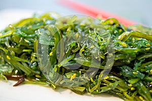 Green fresh oriental seaweed salad served with chopsticks