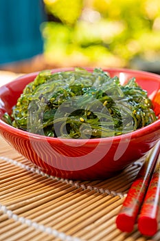 Green fresh oriental seaweed salad served with chopsticks