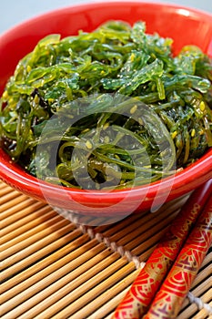 Green fresh oriental seaweed salad served with chopsticks