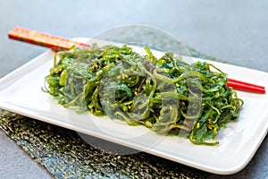 Green fresh oriental seaweed salad served with chopsticks