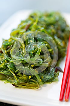 Green fresh oriental seaweed salad served with chopsticks