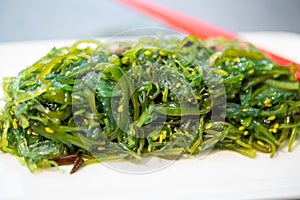 Green fresh oriental seaweed salad served with chopsticks