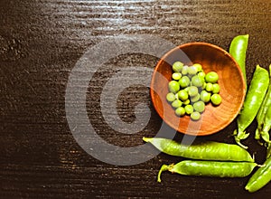 Green fresh peas in wooden plate