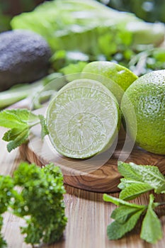 Green fruit and vegetable - wooden board with green food  ingredients: garlic, avocado, lime, mint, cilantro, leek, green chili