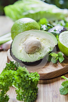 Green fruit and vegetable - wooden board with green food  ingredients: garlic, avocado, lime, mint, cilantro, leek, green chili