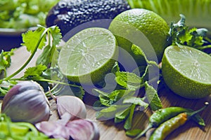 Green fruit and vegetable - wooden board with green food  ingredients: garlic, avocado, lime, mint, cilantro, leek, green chili