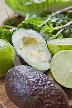 Green fruit and vegetable - wooden board with green food  ingredients: garlic, avocado, lime, mint, cilantro, leek, green chili