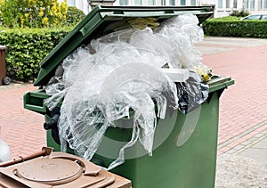 green garbage container bin overflowing with plastic packaging waste