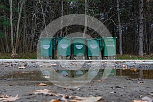 Green garbage containers in the forest in a row