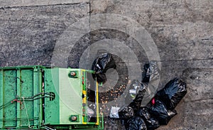 Green garbage truck Collecting a large number of black garbage bags that are tied up On the sidewalk To discard Viewed from the to