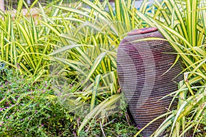 Green garden decoration with clay pottery fountain. Old clay jar