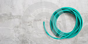 Green garden hose on concrete background