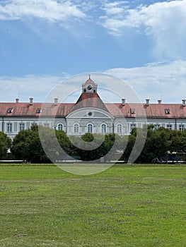 Green garden of Nymphenburg Palace lined with lush trees. Munich, Germany.