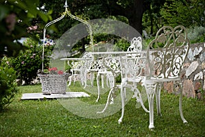 Green garden with white Victorian metal table and chairs