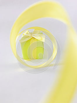 Green Gift box at the end of the spiral yellow ribbon, white background, vertical.