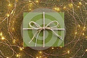 Green gift box and festive glowing lights on knitted background