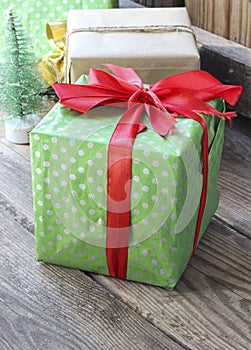 Green gift box with red ribbon on a wooden background