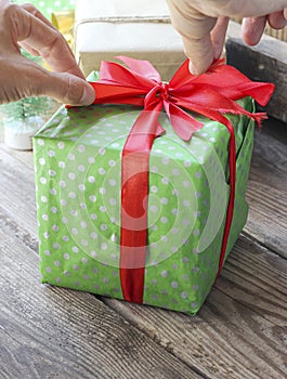 Green gift box with red ribbon on a wooden background
