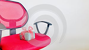 A Green gift box on red wheels office chair over white background.