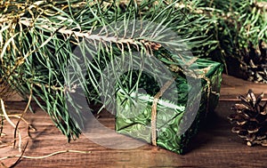 Green gift box under Christmas tree branches