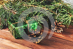 Green gift box under Christmas tree branches