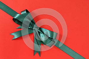 Green gift ribbon bow corner diagonal on red paper background