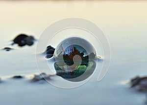 A green glass bead in the water reflecting the light