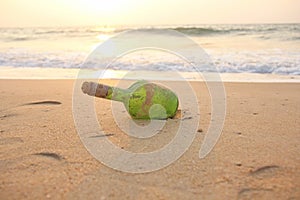 Green glass bottle with a message inside on the seashore on the beach. Magic and fairy tale. Design with copy space