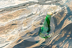Green glass bottle in the sea with a message.