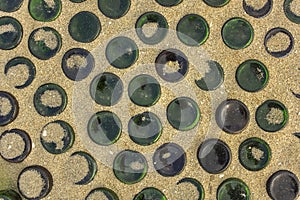 Green glass bottles protrude from the sand a round bottom up. rough surface texture photo