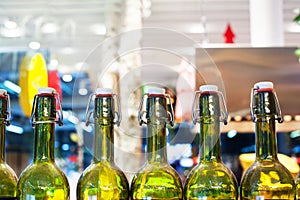 Green glass bottles of wine in line on wooden shelf, bar interior design, wine tasting concept, nightlife style, winery production