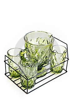 green glass carafe and glasses for drinks in a metal basket. set of tableware